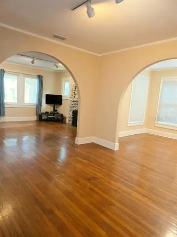 a view of empty room with wooden floor and a window