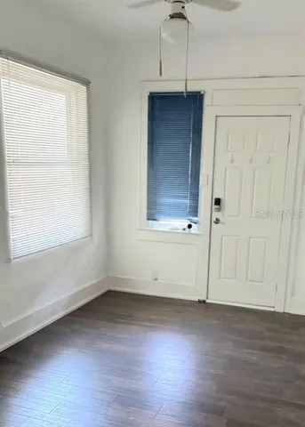 an empty room with wooden floor and windows