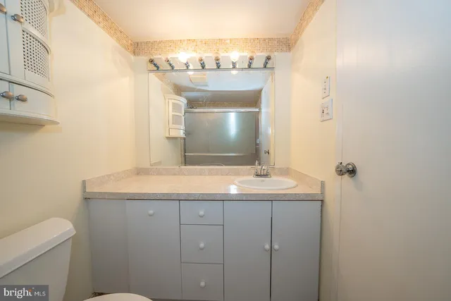 a bathroom with a granite countertop sink a toilet and a mirror