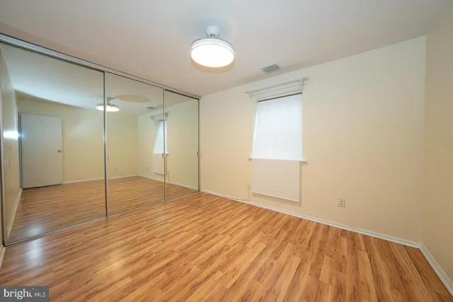 a view of an empty room with wooden floor and a bathroom