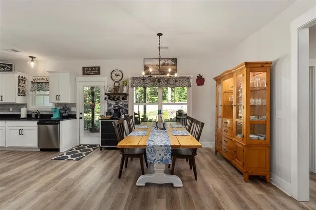 a view of a dining room and livingroom with furniture wooden floor a chandelier