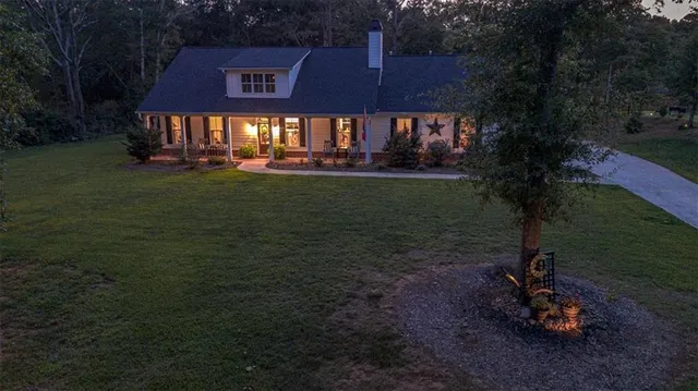 a view of a house with a yard potted plants and a bench