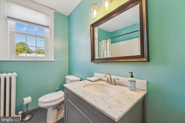 a bathroom with a granite countertop toilet sink and mirror