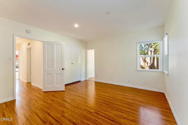 a view of an empty room with wooden floor and window