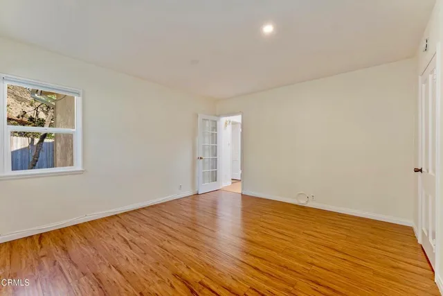 a view of an empty room with wooden floor and a window