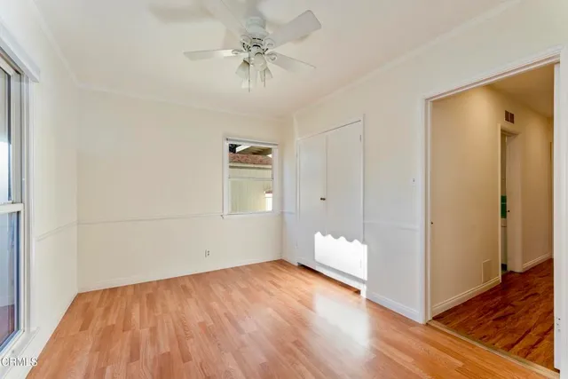 a view of empty room with wooden floor and fan