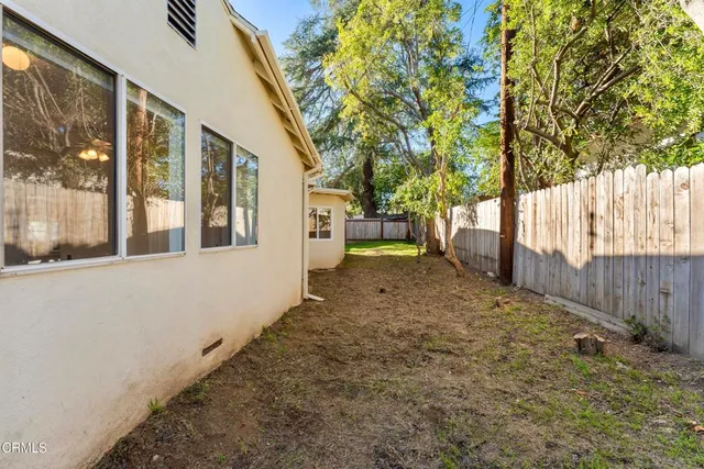 a view of a backyard with large trees and wooden fence