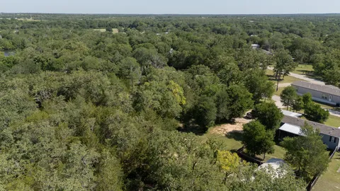 an aerial view of residential house with outdoor space and trees all around