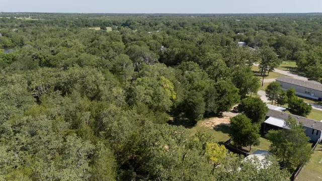 an aerial view of residential house with outdoor space and trees all around