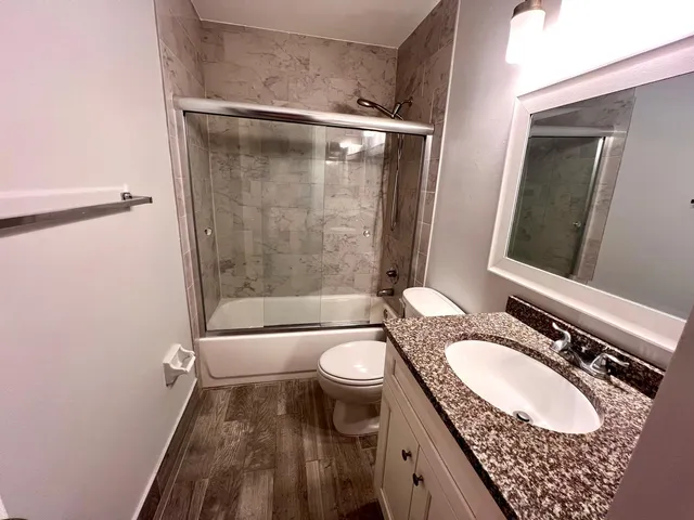 a bathroom with a granite countertop sink toilet and shower