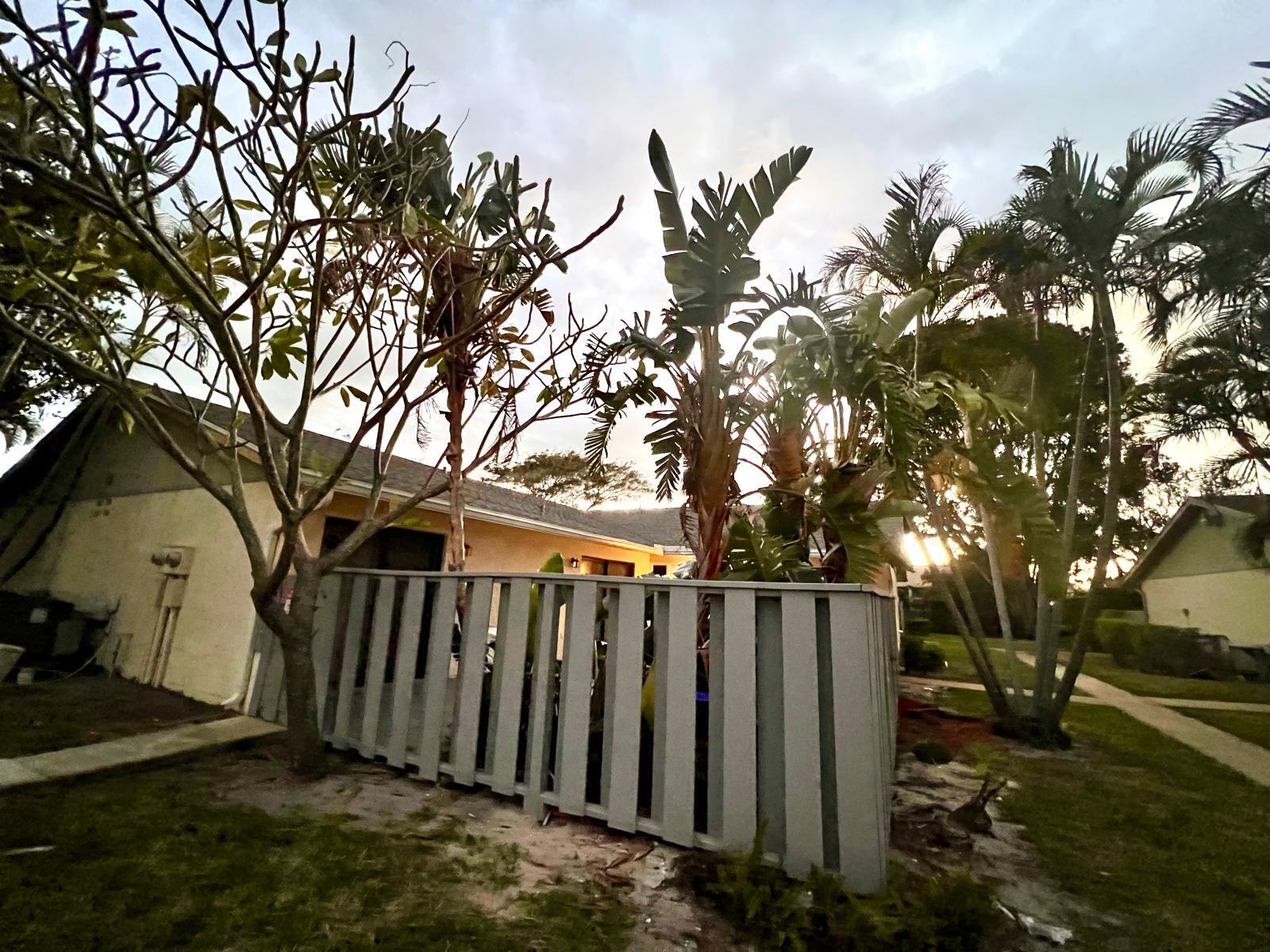 8113 Ambach Way, Unit 28A Hypoluxo, FL 33462 - Photo 14 of 20 a view of a backyard with wooden fence and a large tree