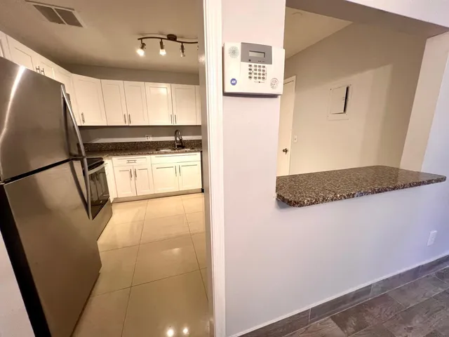 a kitchen with a refrigerator and white cabinets