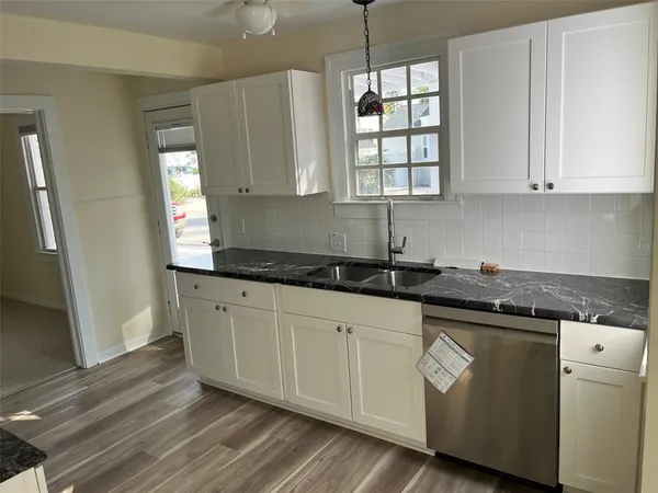 a kitchen with stainless steel appliances granite countertop a sink a stove and white cabinets with wooden floor