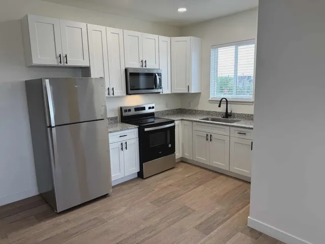 a kitchen with white cabinets sink and stainless steel appliances