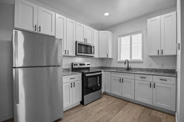 a kitchen with stainless steel appliances granite countertop a refrigerator stove a sink and dishwasher with wooden floor