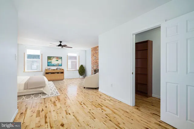 a spacious bedroom with a bed a dresser and a large window