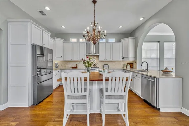 a kitchen with stainless steel appliances granite countertop a kitchen island hardwood floor sink stove and white cabinets