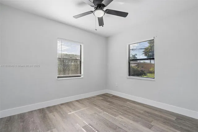 a view of an empty room with a window and wooden floor