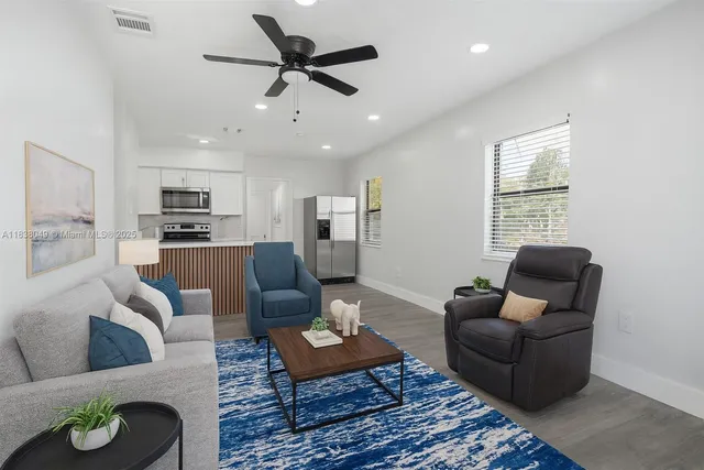 a living room with furniture kitchen view and a window