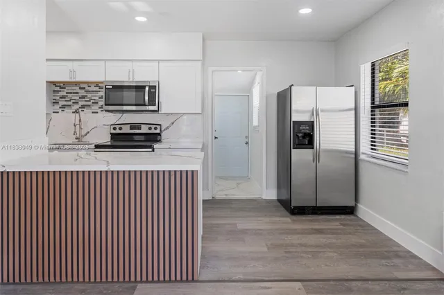 a kitchen with stainless steel appliances granite countertop a refrigerator a stove and a sink