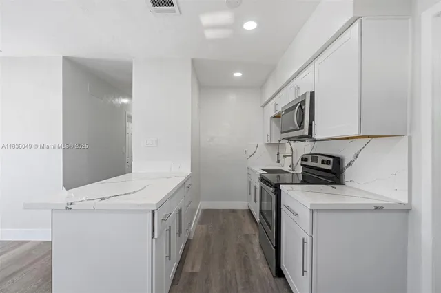 a kitchen with a sink a stove top oven and white cabinets