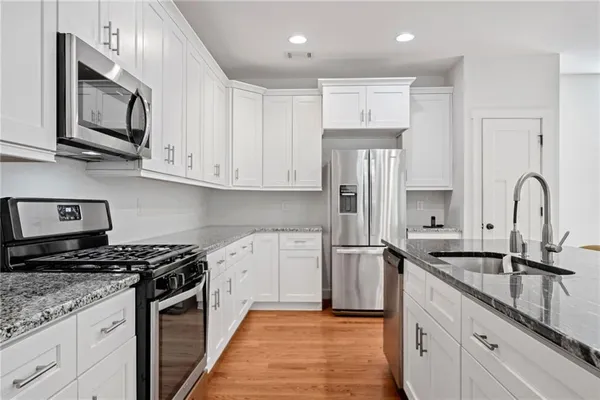 a kitchen with stainless steel appliances granite countertop a table chairs sink and cabinets