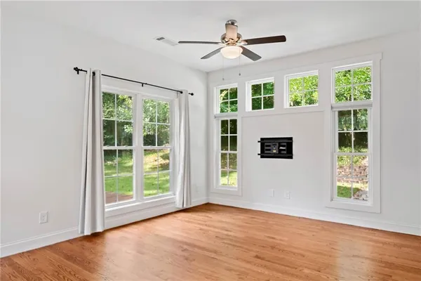 an empty room with wooden floor and windows