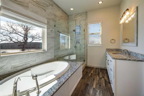 a bathroom with a granite countertop tub sink and mirror