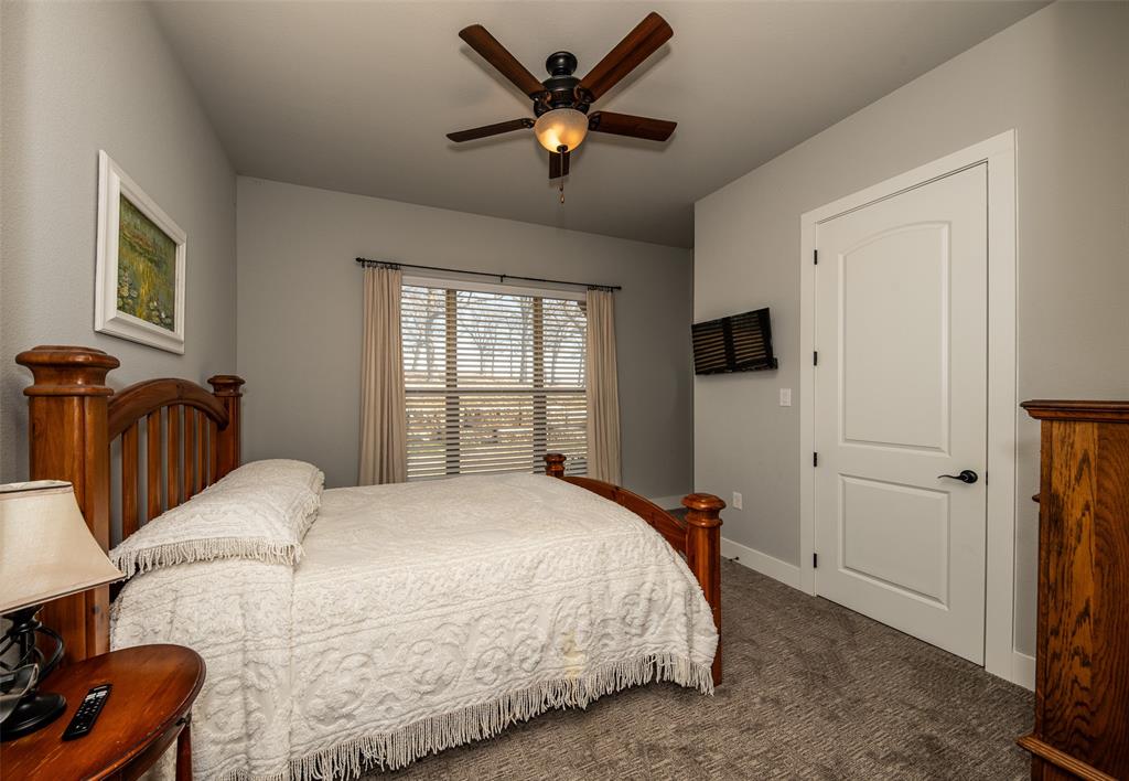 133 Sunset Bay Pointe Court Chico, TX 76431 - Photo 21 of 40 Bedroom featuring a ceiling fan, dark colored carpet, and baseboards