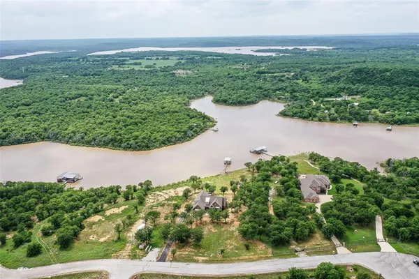 an aerial view of a house with a yard and lake view in back