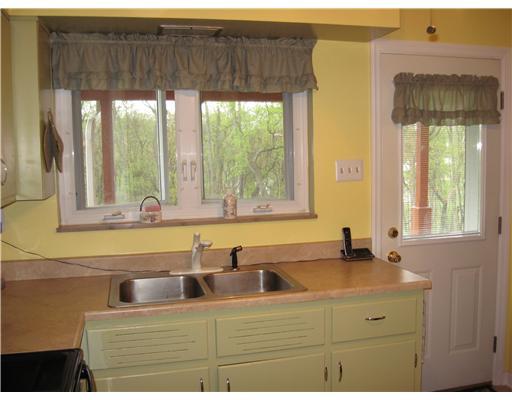 3062 Clay Pike Rillton, PA 15678 - Photo 11 of 18 Kitchen. Other side of Kitchen space... Door goes onto deck off of back of house. There is a door next to that exit that leads down into the basement! AGAIN... WINDOWS!! Notice the trees outside, PRIVACY!