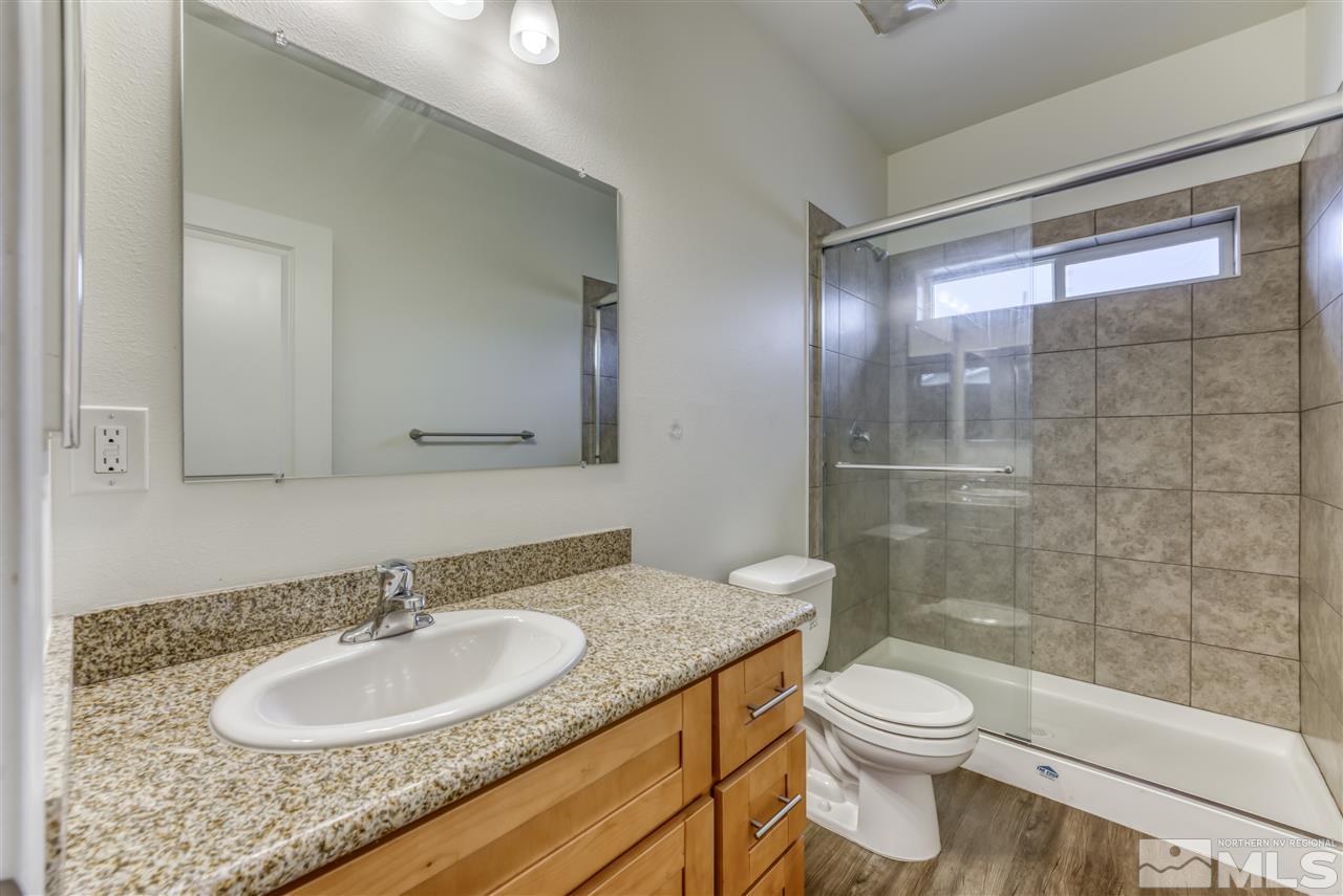820 Vassar Street Reno, NV 89502 - Photo 18 of 29 a bathroom with a granite countertop sink toilet a mirror and shower