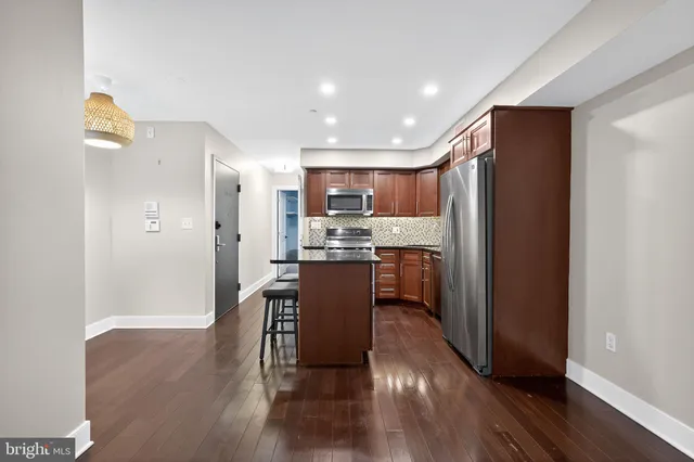 a kitchen with kitchen island wooden floors appliances and cabinets