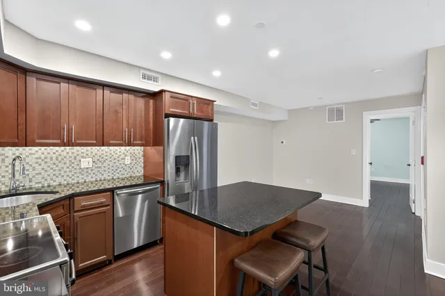a kitchen with stainless steel appliances granite countertop a table chairs and a refrigerator