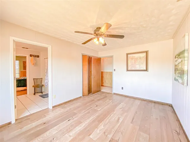 a view of empty room with wooden floor and fan