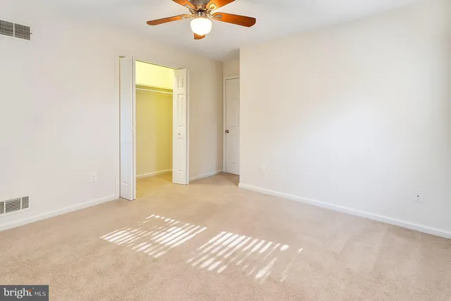 an empty room with a chandelier fan and a window