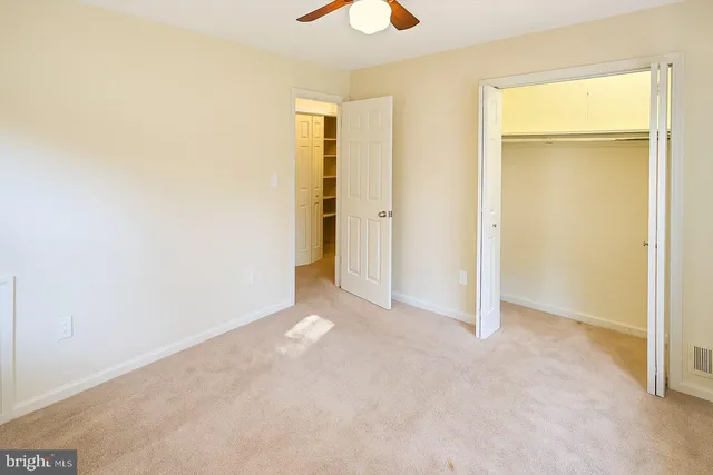 a view of an empty room with closet and a chandelier fan