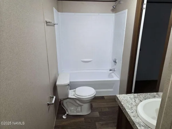 a bathroom with a granite countertop toilet and a sink