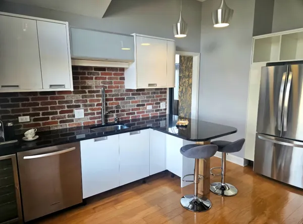 a kitchen with stainless steel appliances wooden floor and a sink