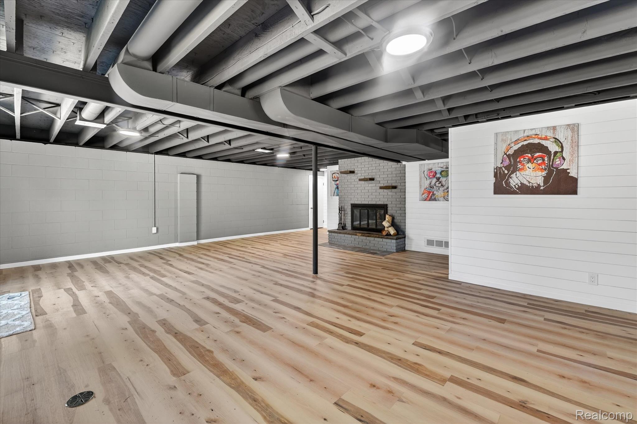2250 Montague Road Davison, MI 48423 - Photo 31 of 45 Finished lower level featuring light wood-finish flooring, exposed painted ceiling joists, and a brick fireplace