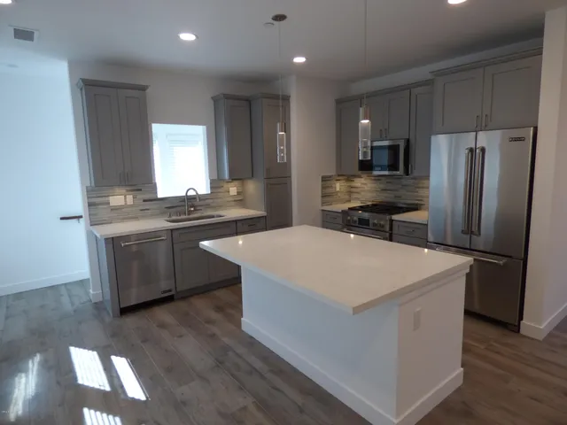 a kitchen with stainless steel appliances a sink a stove a refrigerator and cabinets