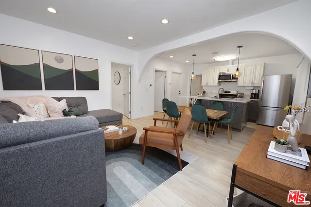 a living room with furniture kitchen view and a wooden floor