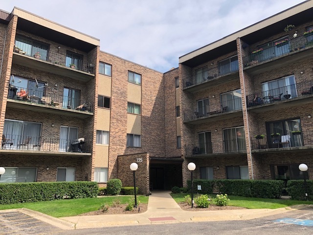 a front view of a building with a garden and plants