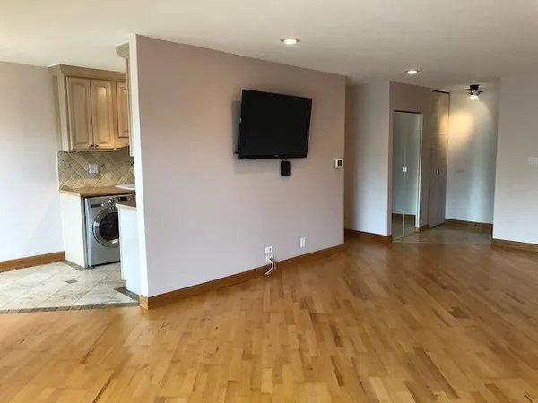 a view of a livingroom with wooden floor and a flat screen tv