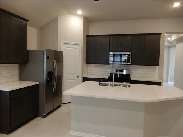 a kitchen with a sink a refrigerator and cabinets