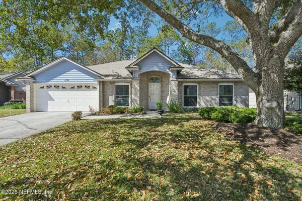 a front view of a house with a yard and large tree