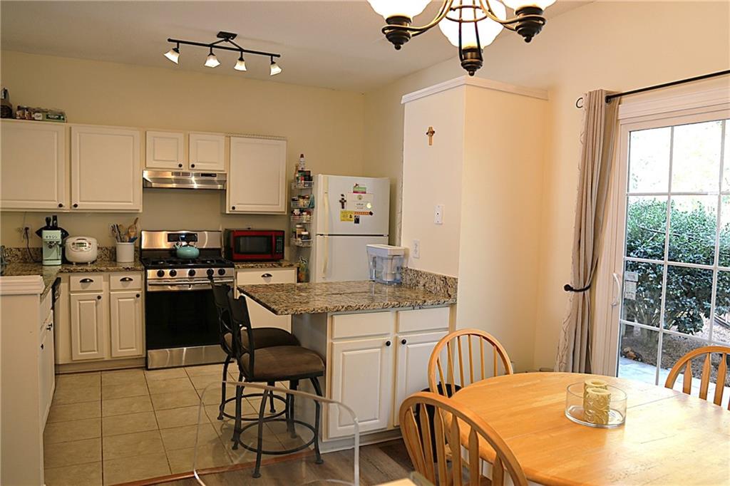 3767 Berkeley Crossing Duluth, GA 30096 - Photo 8 of 23 a kitchen with stainless steel appliances granite countertop a sink dishwasher a stove a refrigerator a dining table and chairs with wooden floor