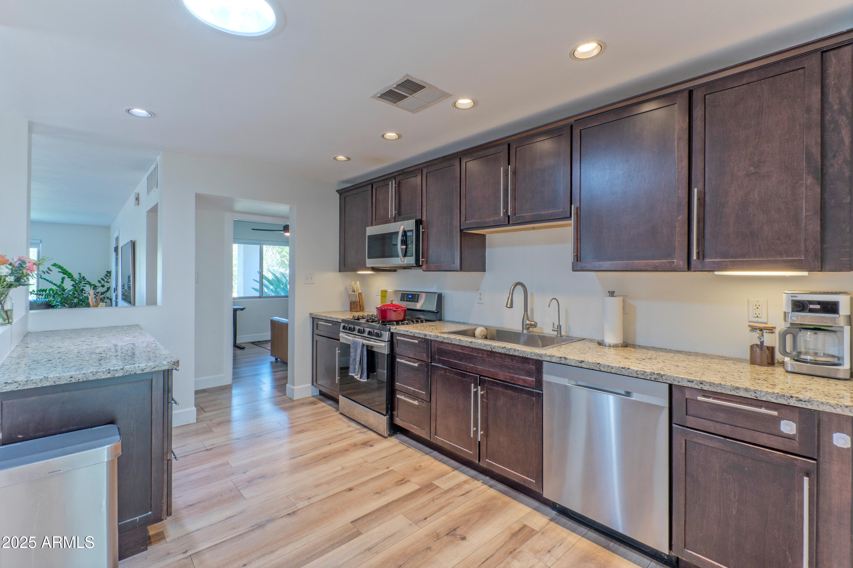 4229 North 34th Street Phoenix, AZ 85018 - Photo 5 of 20 a kitchen with kitchen island granite countertop a sink cabinets and wooden floor