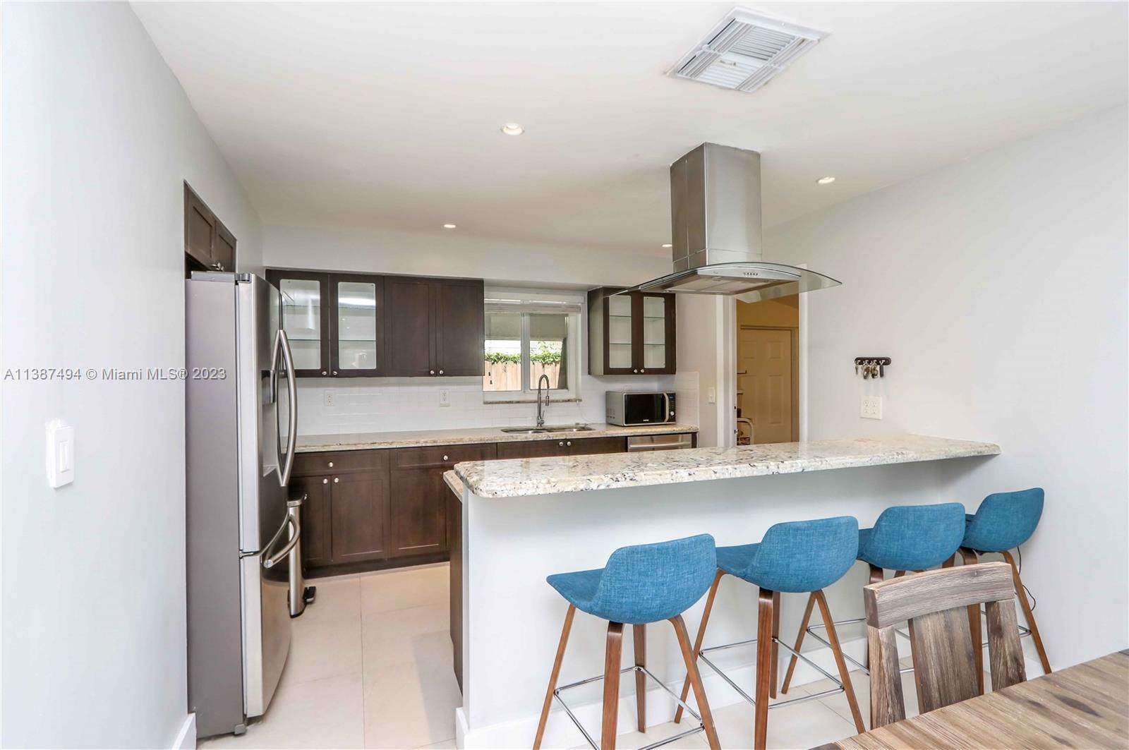 9275 Southwest 45th Street Miami, FL 33165 - Photo 8 of 23 a kitchen with stainless steel appliances kitchen island granite countertop a table and chairs in it