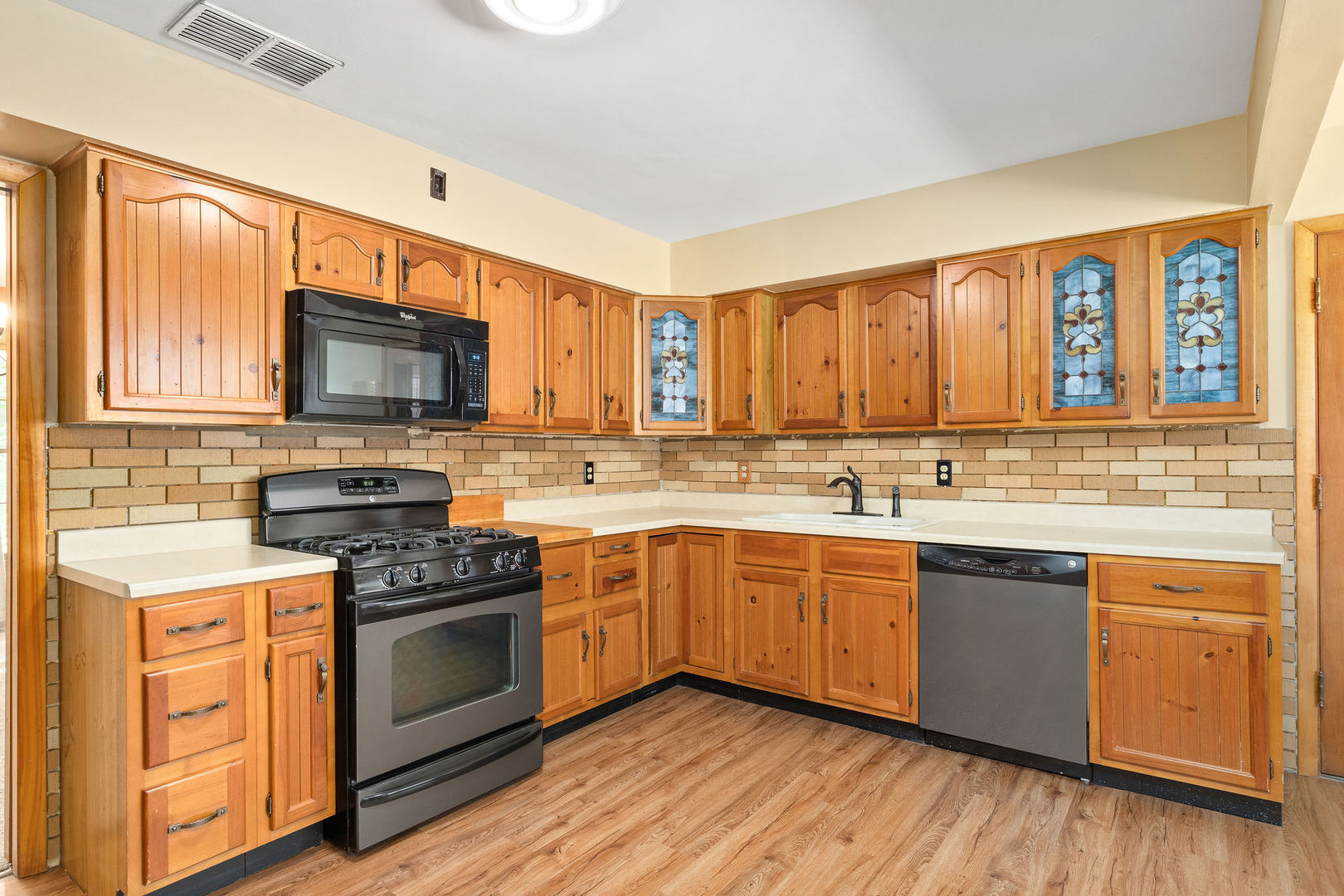 202 Sears Street Plano, IL 60545 - Photo 8 of 32 a kitchen with stainless steel appliances granite countertop wooden cabinets a sink dishwasher a stove and a refrigerator with wooden floor